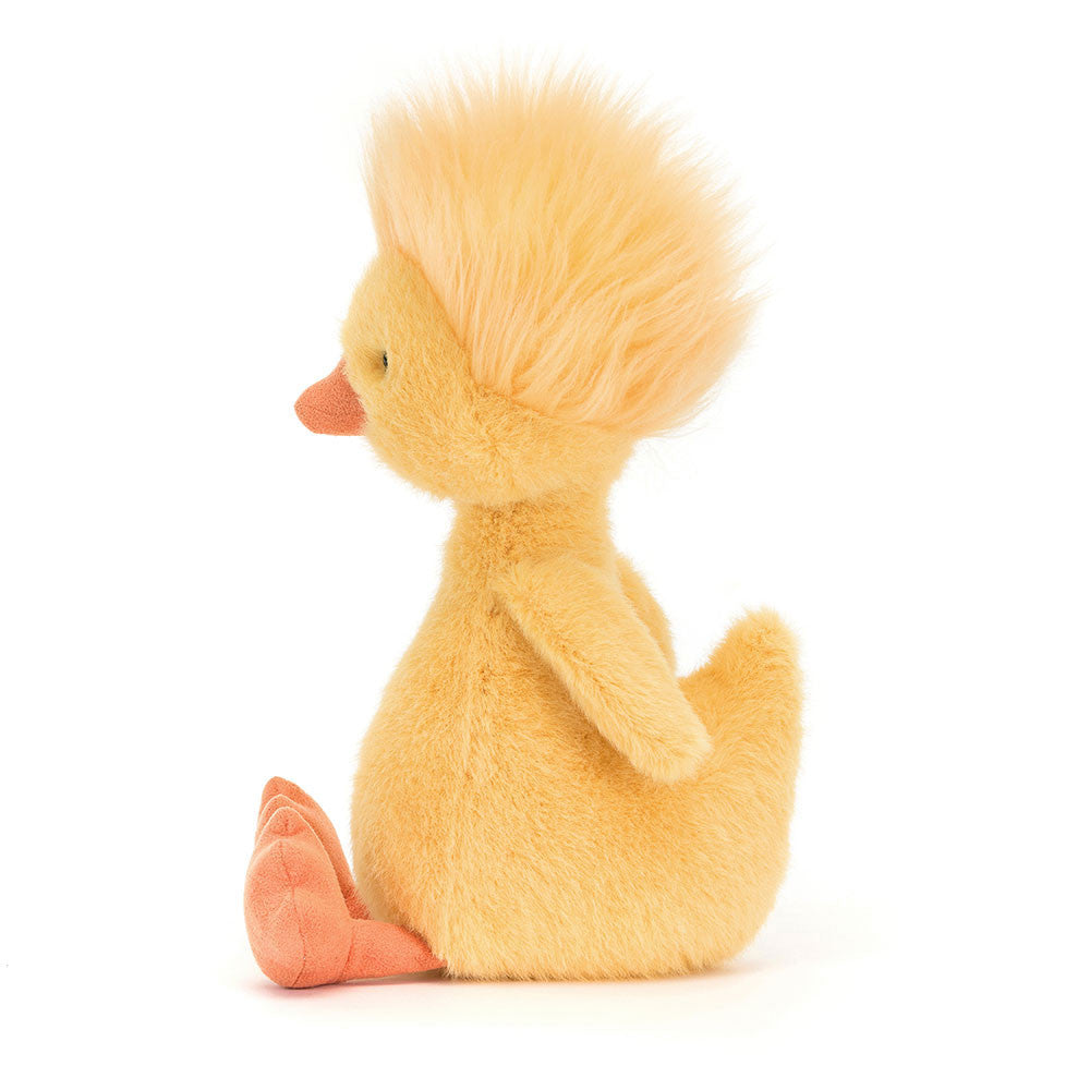 Side view of Jellycat branded plush bright yellow duck soft toy, with an orange beak and feet, and a big tuft of yellow hair, sitting on a white background.