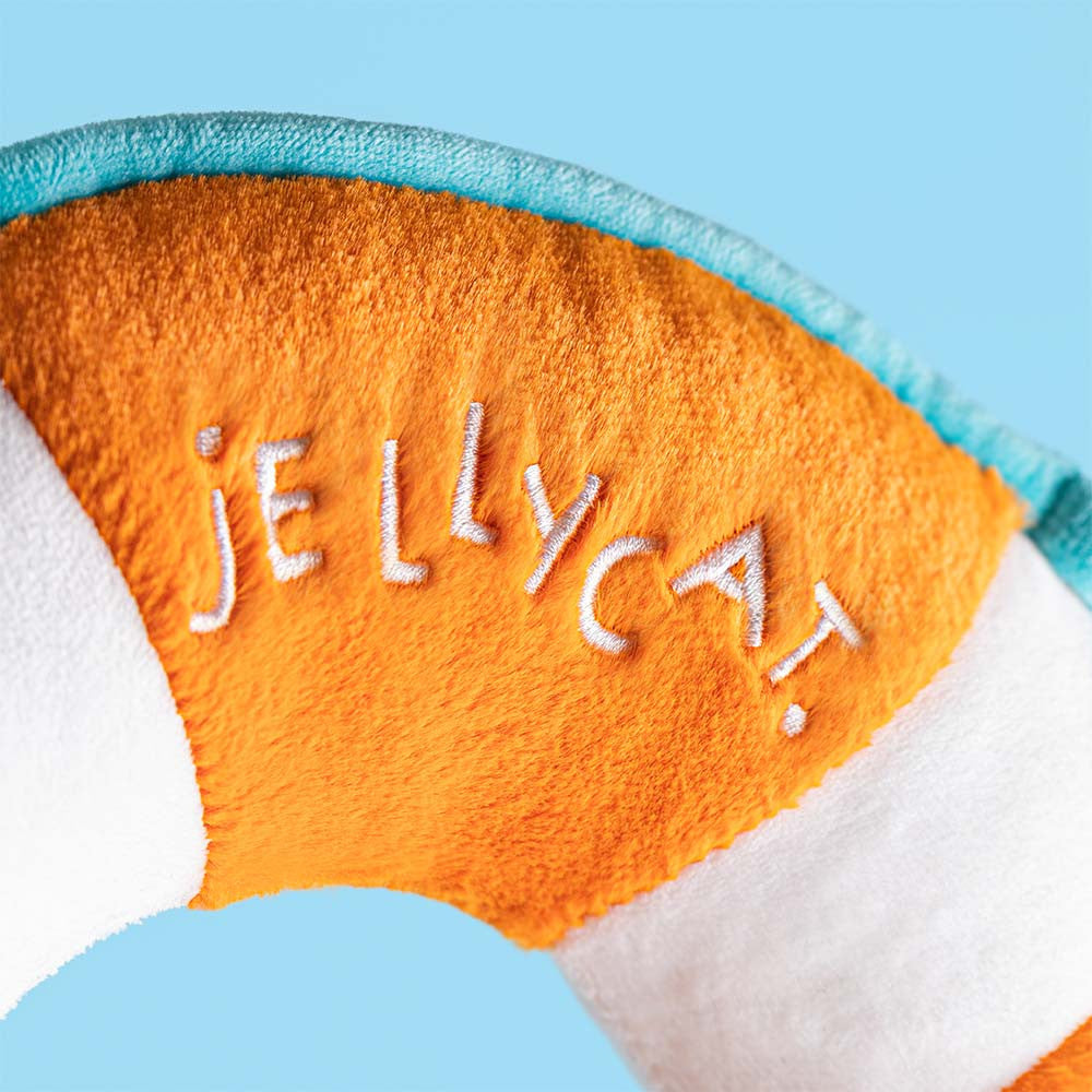 Close-up of Amuseables Life Ring showing embroidered Jellycat lettering, orange plush fabric and turquoise edging.